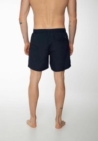 Shorts de bain bleu marine en matériau léger, avec une taille élastique et une poche zippée au dos. Design minimaliste et couleur unie.