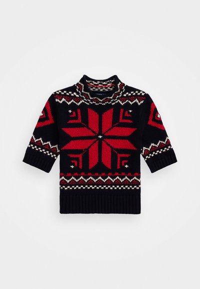 Adīta džemperis ar augstu apkakli, īsām piedurknēm, tumši zila pamatne, kas rotāta ar lielu sarkanu sniegpārsliņu rakstu un ģeometriskām akcentiem sarkanā un krēmkrāsā.