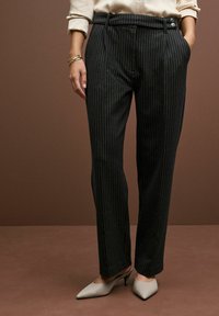 Schwarze, gestreifte Hose mit taillierter Passform, flachem Vorderteil, seitlichen Taschen und einer Knopfdetaillierung an der Taille.