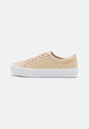 Beige lav-sko sneaker med hvid tyk gummisål, tekstureret overdel, snørelukning og polstret krave vist fra siden på en hvid baggrund.