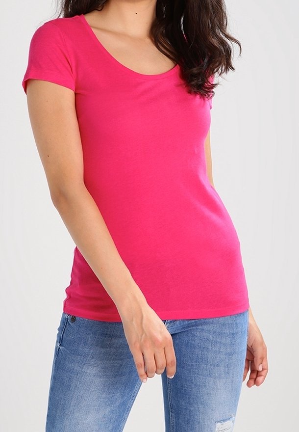Camiseta ajustada de manga corta en algodón de color rosa brillante, con escote redondeado. Combinada con jeans claros, desgastados.