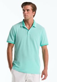Polo vert d'eau clair avec un plastron à deux boutons, des manches courtes et des accents de col rayés. Fabriqué à partir d'un tissu doux et texturé.