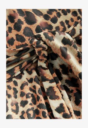 Tkanina w leopardzie w kolorze pomarańczowym, brązowym i czarnym na beżowym tle. Teksturowana i zawieszona z warkoczem.