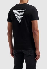 Zwarte katoenen t-shirt met een groot wit gestreept driehoekig grafisch ontwerp op de achterkant. Korte mouwen en een klassieke ronde hals.