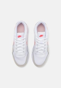 Bijele tenisice s mrežastim dizajnom, s ružičastim akcentima i Nike logom na jeziku. S vezicama bijele boje, sivoj potplatu.