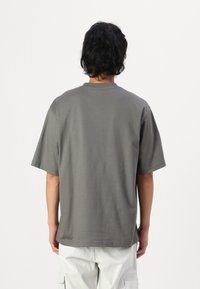 T-shirt gris à manches courtes vu de dos, en coton, avec un col rond et une coupe décontractée, au toucher lisse.