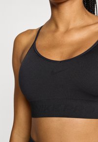 Μαύρο αθλητικό μπουστάκι με λεπτές τιράντες και στρογγυλεμένο ντεκολτέ. Διαθέτει μαλακό, απαλό ύφασμ α και λωρίδα με το λογότυπο "NIKE PRO".