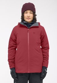 Veste isolée rouge avec doublure intérieure grise, fermeture éclair à l'avant, capuche ajustable et gants noirs avec motif de grip texturé.
