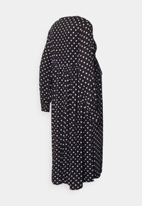 Vestido preto com bolinhas roxas, mangas longas, decote redondo, saia evasê e bolsos, com uma textura de tecido fluida.