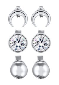 Deux paires de boucles d'oreilles en argent : une paire avec des formes de croissant, l'autre avec des cristaux transparents ronds sertis dans une base en métal lisse.