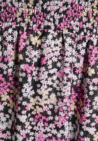 Tissu noir avec une texture froncée, recouvert de petits imprimés floraux roses, blancs et beiges, avec un cousu élastique froncé en haut.