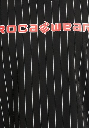 Black striped t-shirt featuring white vertical lines, with bold red "Rocawear" graphic text across the chest. Cotton material texture.