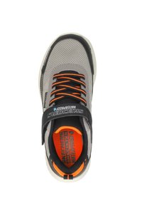 Zapatilla deportiva gris con parte superior de malla, acentos en negro y naranja, cordones elásticos, suela acolchada y marca "Skechers WaterProof".