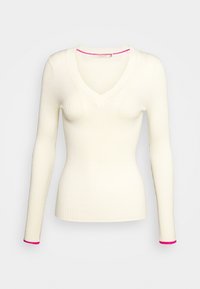 Crème rib gebreide lange mouw trui met V-hals en roze afwerking op de manchetten en de halslijn, aangesloten silhouet, effen achtergrond.