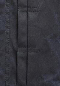 Tecido preto com uma textura suave, com costuras horizontais e duas tiras verticais de tecido para fecho.