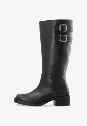 Botte en cuir noire mi-mollet avec talon bloc bas et deux sangles à boucle argentées près du haut sur le côté extérieur.