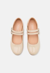Beżowe lakierowane buty Mary Jane z dwoma regulowanymi paskami i zaokrąglonym noskiem. Miękka wyściółka wnętrza i antypoślizgowa podeszwa zapewniają komfort.