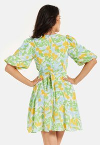 Short-sleeved dress featuring a pastel blue background with yellow tulip and green floral patterns, a fitted waist, and a flared skirt.