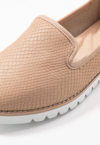 Scarpa beige slip-on realizzata in finta pelle testurizzata con motivo in pelle di serpente, dotata di una soletta imbottita e di una suola in gomma bianca.