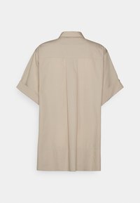 Beige Kurzarmhemd mit Kragen, ausgestattet mit einer Rückfalte, aufgerollten Ärmeln und einer glatten Stofftextur.