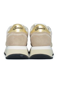 Sneakers in suede beige e rete bianca con un tallone e un logo in accent gold. Suola spessa crema e nera, con strisce bianche.