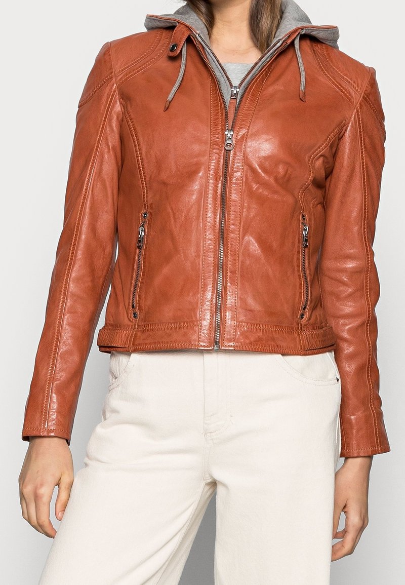 Braune Lederjacke mit grauer Kapuze, Reißverschluss vorne und zwei Seitentaschen; figurbetontes Design mit gesteppten Details an den Schultern.