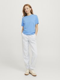 Ljusblå kortärmad t-shirt i kombination med vita mjukisbyxor och beige sneakers, med en avslappnad passform och mjuk bomullstextur.