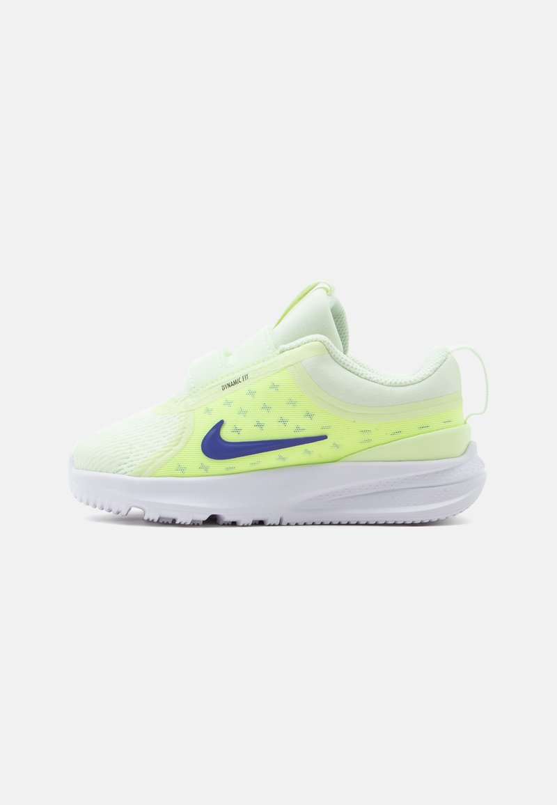 Svetlo zelena in bela atletska obutev z vijoličnim Nike logotipom, mrežastim zgornjim delom, oblazinjeno podplatom in zanko na peti, stranski pogled.