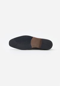 Dark brown leather shoe sole featuring a textured black rubber bottom and a smooth brown heel insert with stitching details.
