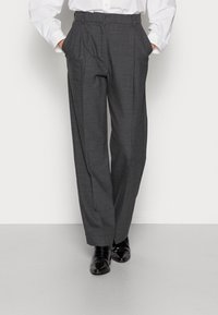 Grijze geplooide broek met een getailleerde pasvorm, voorzien van zijzakken, een gladde textuur en een klassieke tailleband, gecombineerd met glanzende zwarte schoenen.