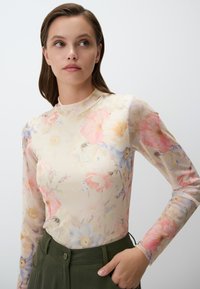 Top lungo a maniche lunghe in tessuto trasparente, con fiori nei toni del rosa pastello, giallo e blu. Collo alto e design aderente.