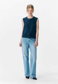 Top sans manches bleu marine avec un col rond et cinq boutons. Assorti à un jean droit bleu clair. Texture lisse et coupe décontractée.