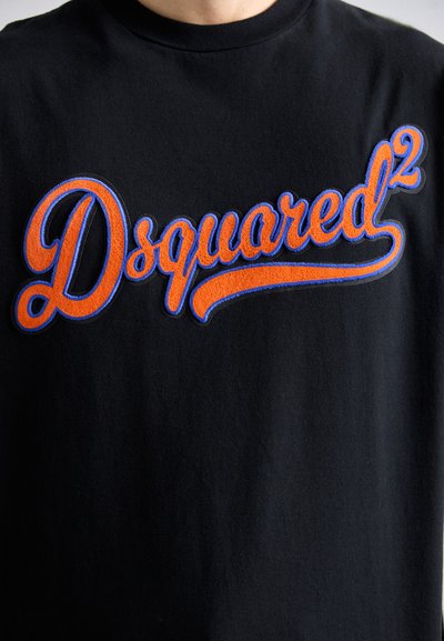 Zwarte T-shirt met groot oranje en blauwe geborduurde "Dsquared²" logo over de borst in cursieve letters.
