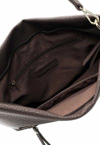 Innenansicht einer braunen, strukturierten Lederhandtasche mit Reißverschlusstasche und flachem Fach, ausgestattet mit einem glatten Stofffutter.