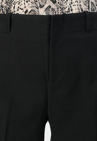 Black pants made of smooth fabric, featuring a flat waistband and side pockets, designed with clean lines and minimal stitching details.