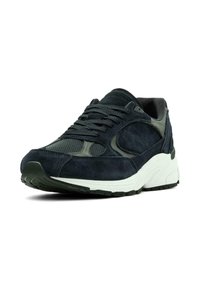 Scarpa sportiva navy e grigia con tomaia in suede, pannelli in mesh e suola bianca con battistrada in gomma nera texturizzata.