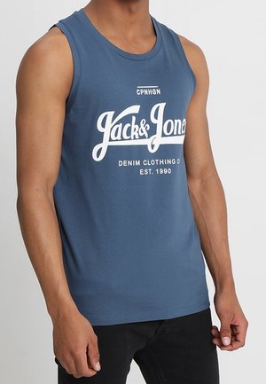 Mann trägt ein blaues ärmelloses Tanktop mit dem Aufdruck "Jack & Jones Denim Clothing Co EST. 1990" auf der Vorderseite.