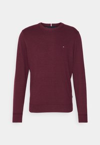 Bordeauxroter Strickpullover mit Rundhalsausschnitt, langen Ärmeln und einem kleinen Logo-Akzent auf der Brust. Glatte Textur und enganliegende Bündchen.