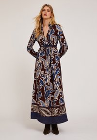 Rochie lungă maro cu motive florale albastre și crema, design tip wrap, mâneci lungi și talie definită. Material neted și tiv până la glezne.