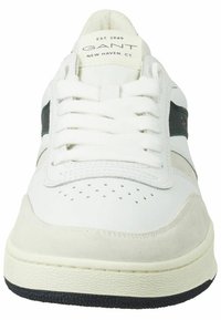 Weißer Sneaker mit einem glatten Leder-Obermaterial, Wildlederakzenten, schwarzem Streifen, durchlöchertem Zehenbereich und strukturiertem Gummisohle. Logo auf der Zunge.
