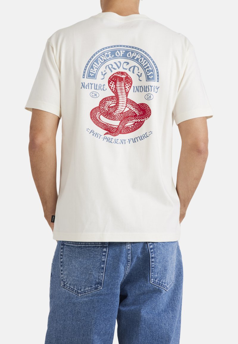 Camiseta de manga corta crema con un gráfico de serpiente roja y azul y texto en la parte posterior. Hecha de una tela suave, con un corte relajado.