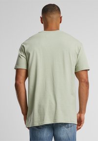 Light green cotton t-shirt with short sleeves, a round neck, and a straight hem. The fabric appears soft and slightly textured.