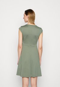 Vestido verde de manga curta com corpete justo e saia rodada. Tecido liso e elástico com decote redondo e design simples.