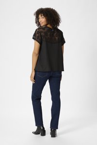 Black blouse with lace detailing on the shoulders and back, paired with dark blue denim jeans and black heeled ankle boots.