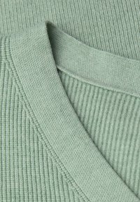 Ljust grönt ribbat trikåtyg med V-ringning och texturerad detaljering. Mjukt, slätt material med ett enhetligt mönster genom hela.