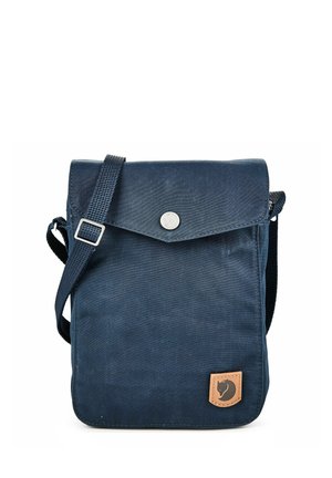 Kleine dunkelblaue Umhängetasche mit verstellbarem Riemen, Klappverschluss mit Druckknopf und kleinem Leder-Logo-Patch unten rechts.