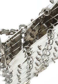 Portafoglio in maglia metallica con anelli interconnessi e pezzi di metallo piatto. La superficie presenta una finitura liscia e lucida di colore argento.