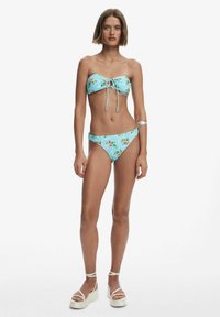 Világoskék virágmintás bikini szett. A felsőrész bandeau stílusú, húzózsinórral, amelyikhez illő alacsony derékú bikini alsó tartozik.