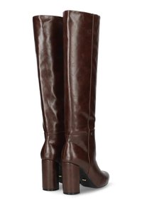 Hoge, donkerbruine leren laarzen met ronde neuzen en stevige hoge hakken, vanaf de achterkant getoond op een witte achtergrond.