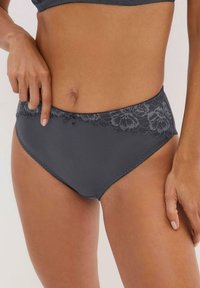 Slip grigi da donna con cinturino in pizzo floreale, texture liscia e un piccolo fiocco decorativo sul davanti. Dettagli di cucitura lungo i bordi.